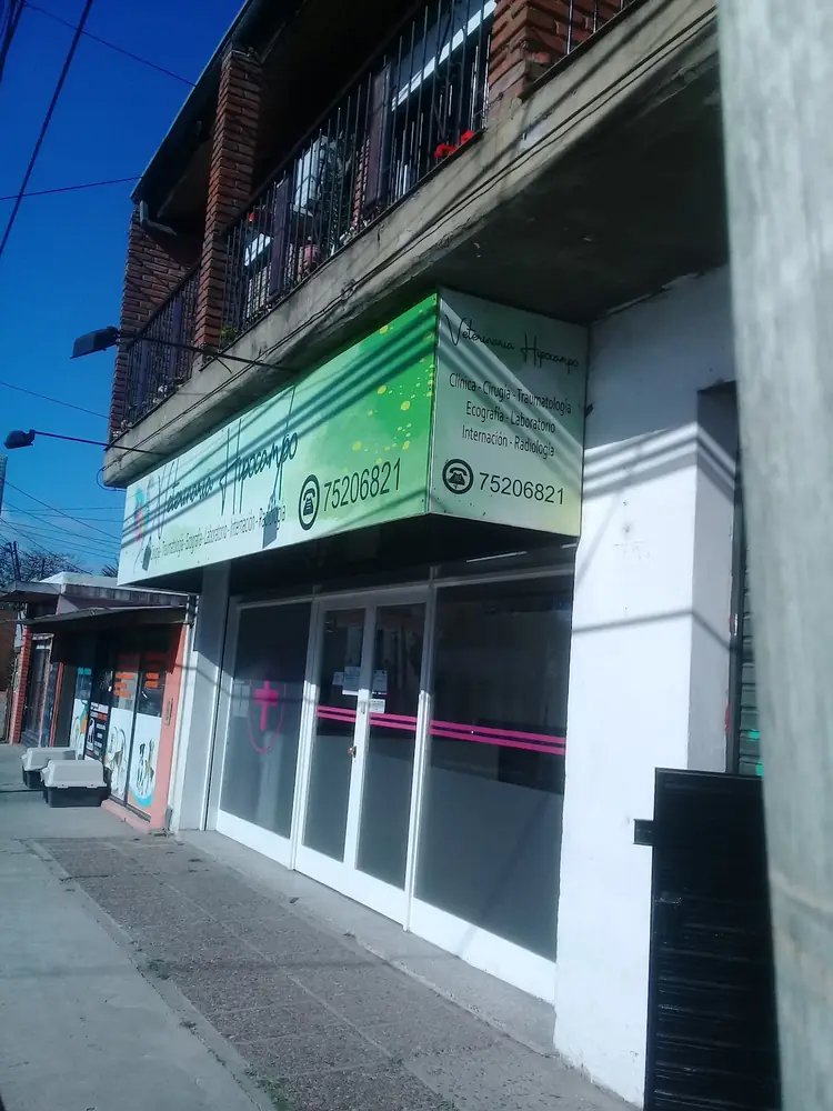 Frente de la veterinaria, con cartel verde y la cruz en la vidriera