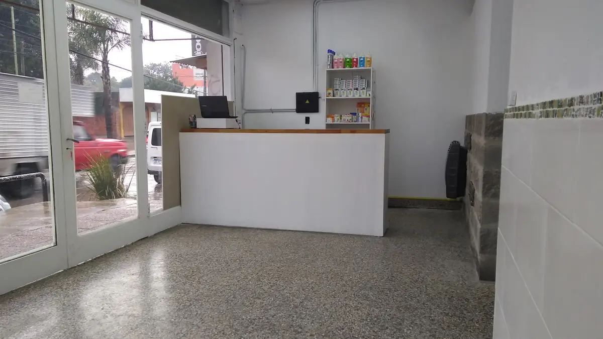 Recepción de la clínica, con mostrador blanco y ventanales a la calle
